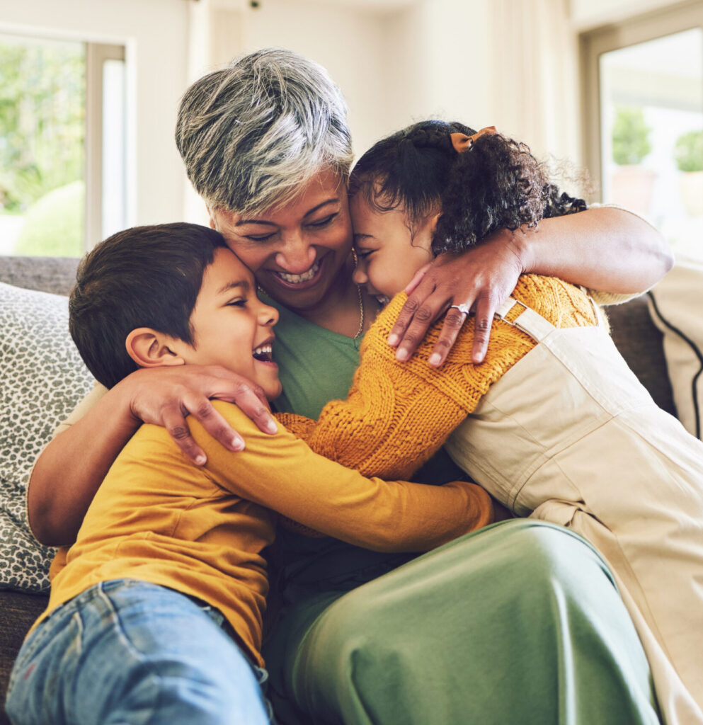 Children laughing and hugging their grandmother.