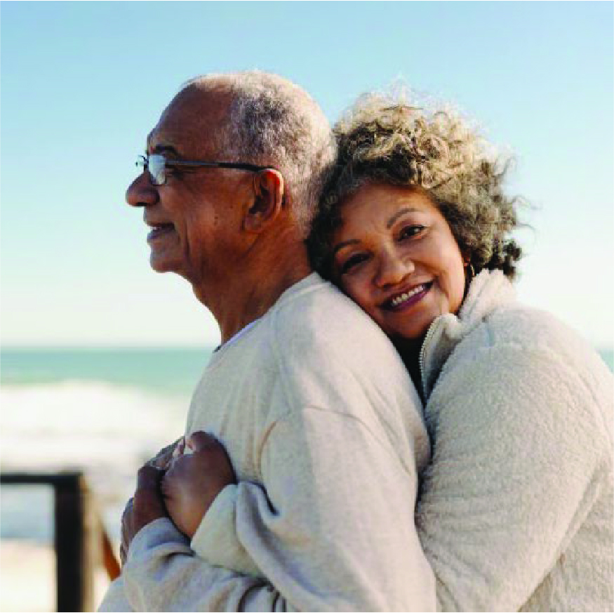 Elderly couple hugging on the beach.