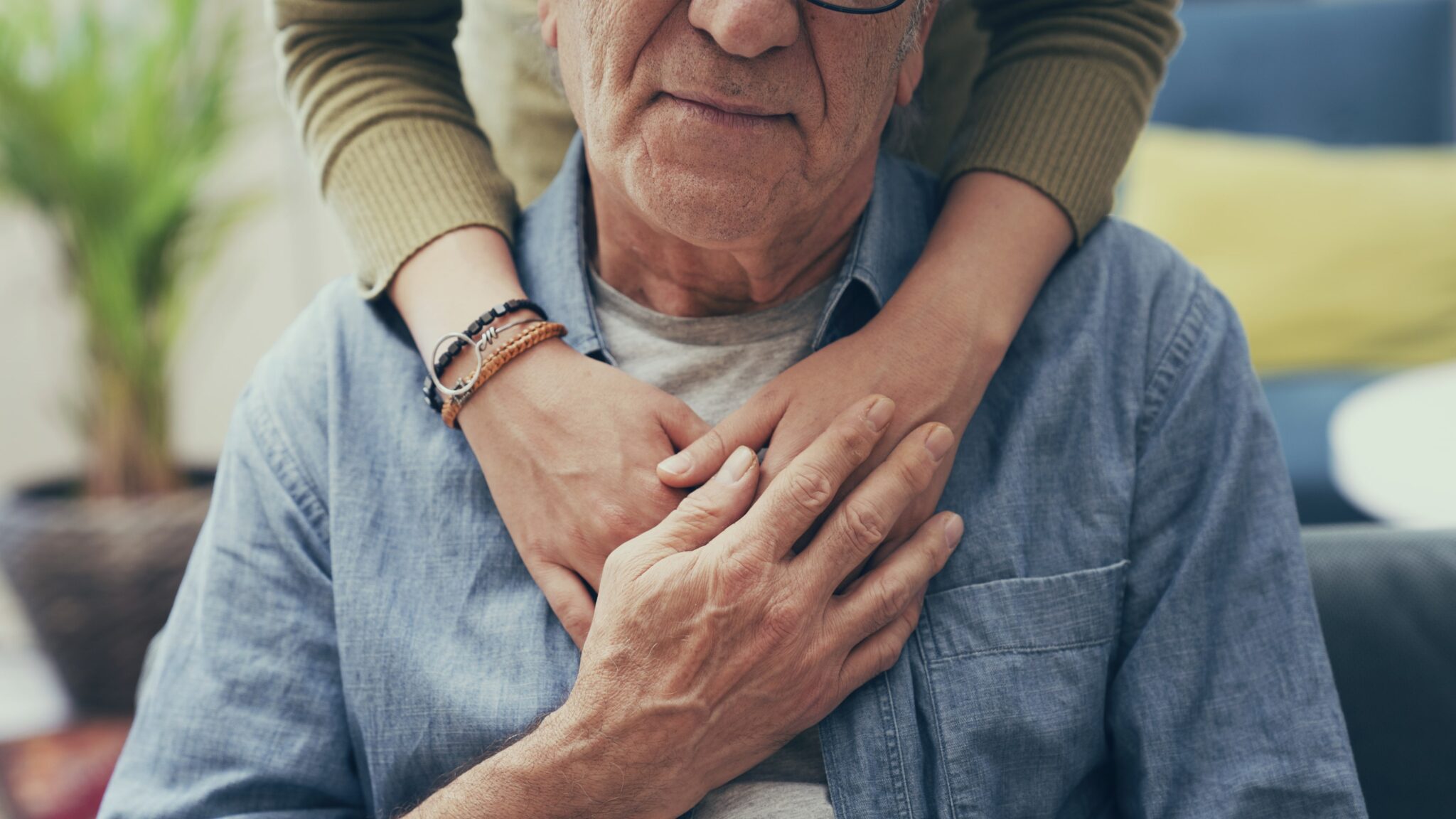 Hands resting on the chest of an elderly man, symbolizing comfort and support.