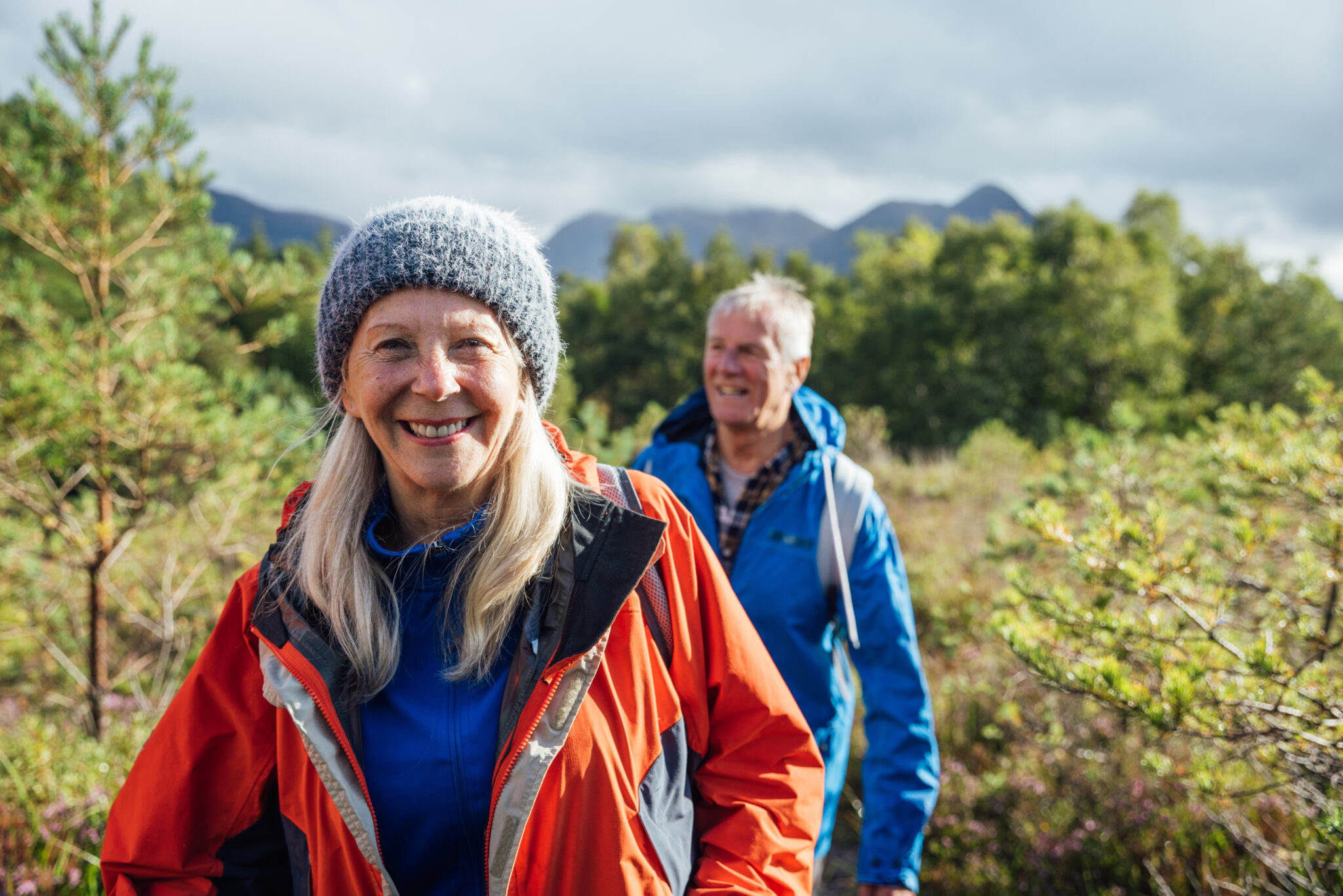 Elderly couple hiking together in the woods.