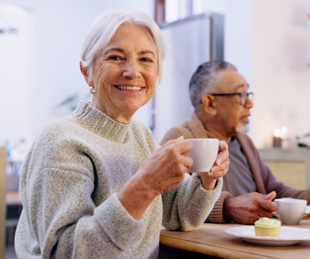 Two elderly people sitting together, one holding a cup of tea.